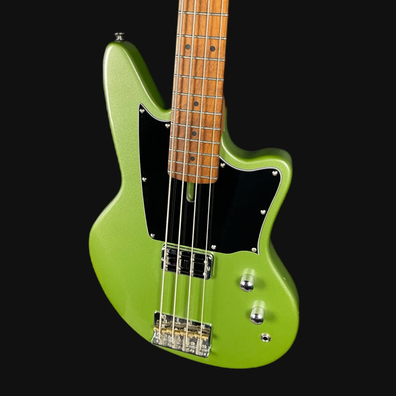 Green electric bass guitar with a black pickguard on a black background