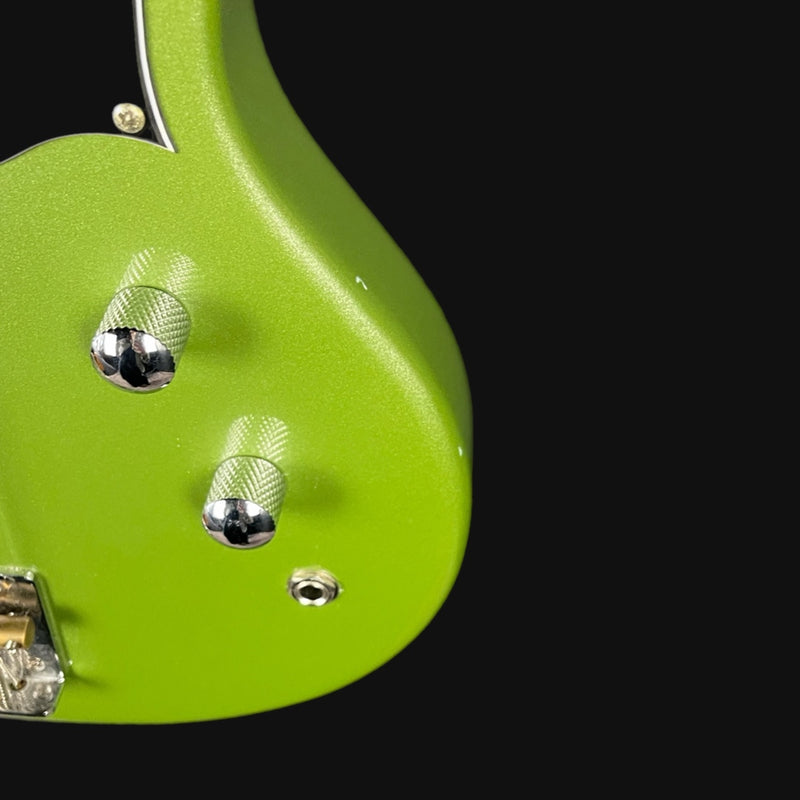 Close-up of a green guitar with metallic hardware on a black background