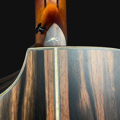 Close-up of a wooden guitar with a brand logo on a black background