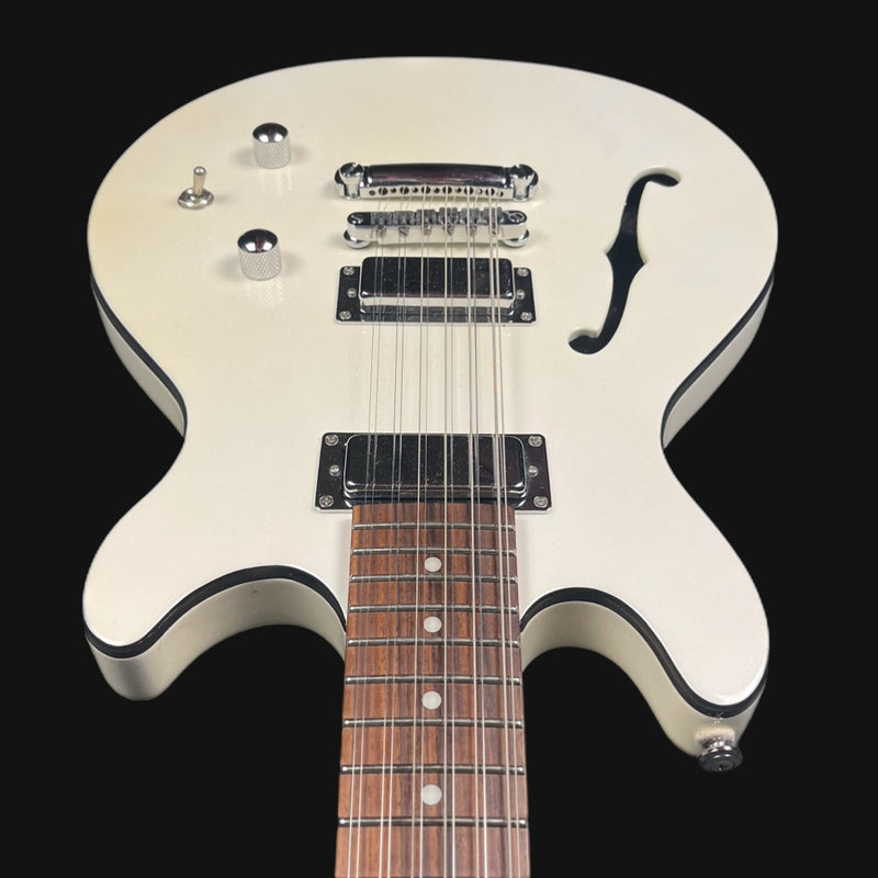 White electric guitar with a black pickguard on a black background
