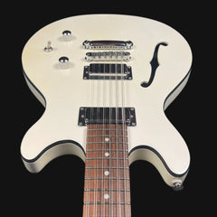 White electric guitar with a black pickguard on a black background