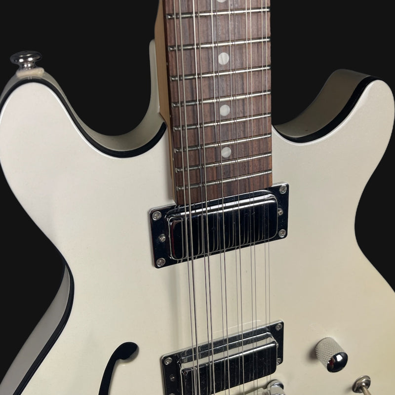 Close-up of a white electric guitar with black accents on a black background