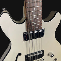Close-up of a white electric guitar with black accents on a black background