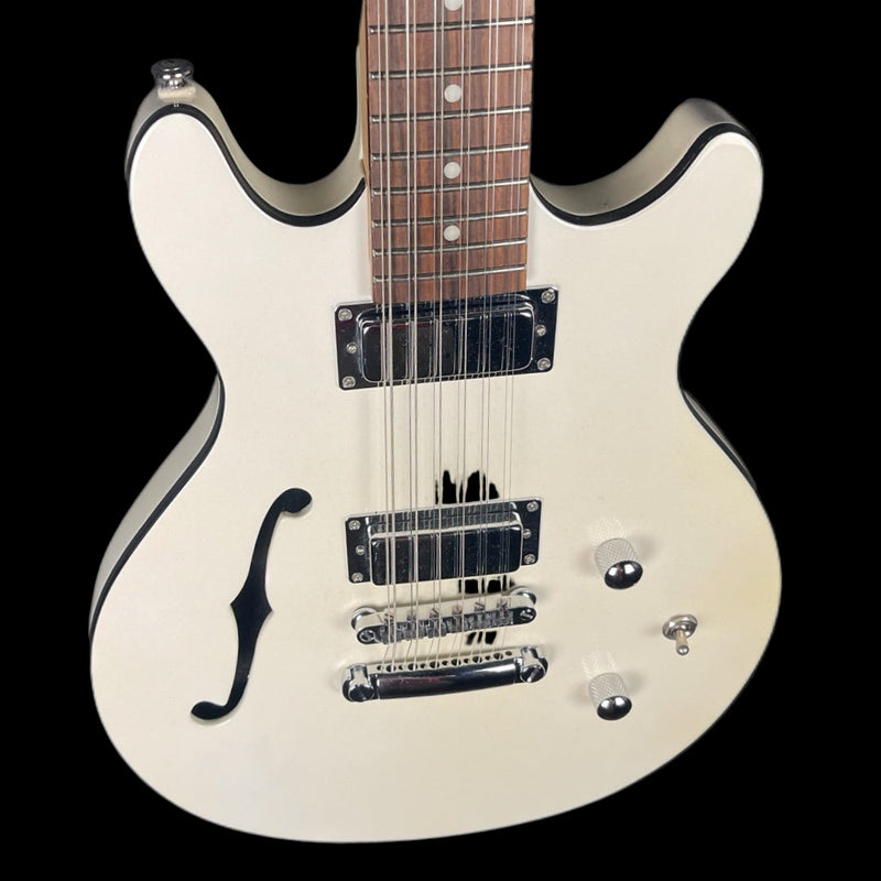 White electric guitar with a black pickguard on a black background
