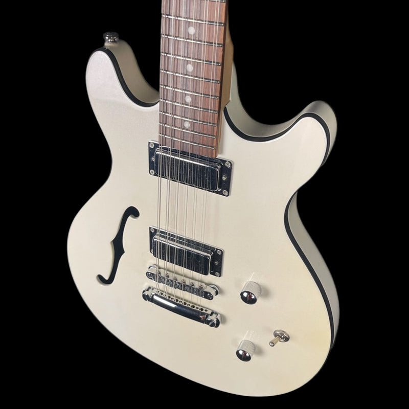 White electric guitar with a black pickguard on a black background