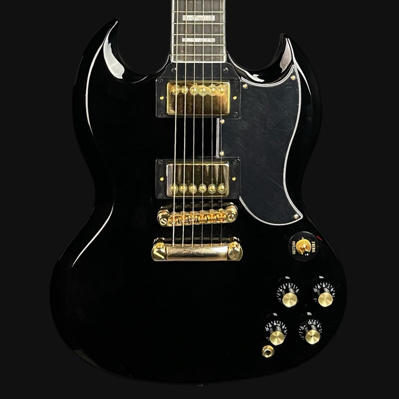Black electric guitar with gold hardware on a black background