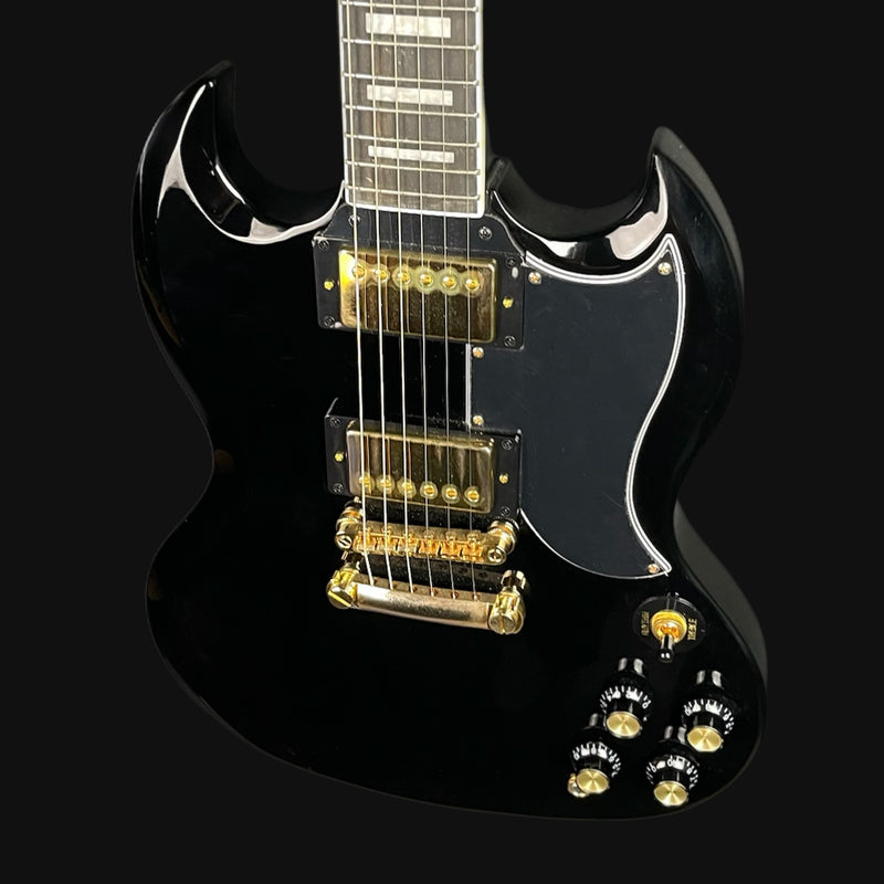 Black electric guitar with gold hardware on a black background