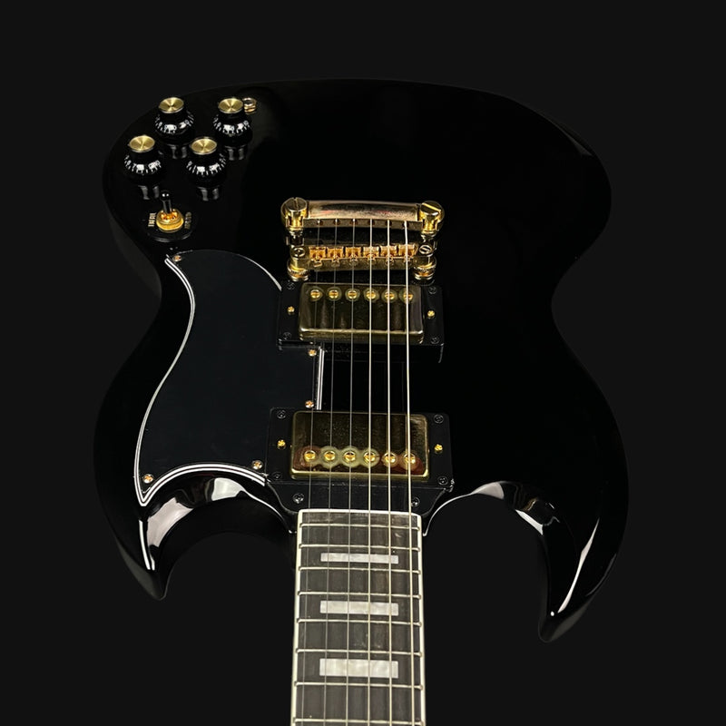 Black electric guitar with gold hardware on a black background