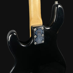 Close-up of a black electric guitar with a visible brand logo on a dark background