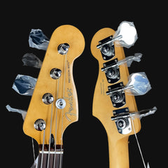 Close-up of a Fender Precision Bass headstock and tuning pegs on a black background