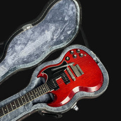 Red electric guitar in a gray case on a black background
