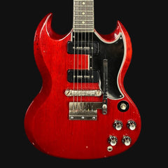 Red electric guitar with a black pickguard on a black background