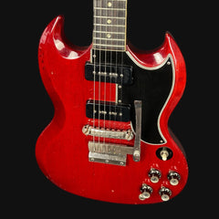 Red electric guitar with a black pickguard on a black background
