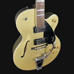 Gold electric guitar with a black pickguard on a black background