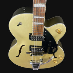 Gold electric guitar with a black pickguard on a black background