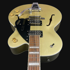 Gold electric guitar with a black pickguard on a black background