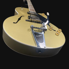 Gold electric guitar with a black pickguard on a black background