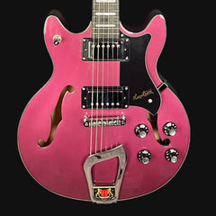 Pink electric guitar with a black pickguard on a black background