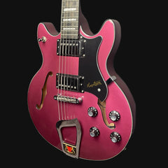 Pink electric guitar with a black pickguard on a black background