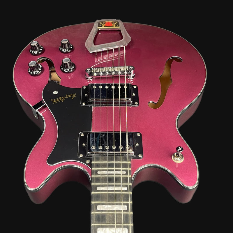 Pink electric guitar with a black pickguard on a black background