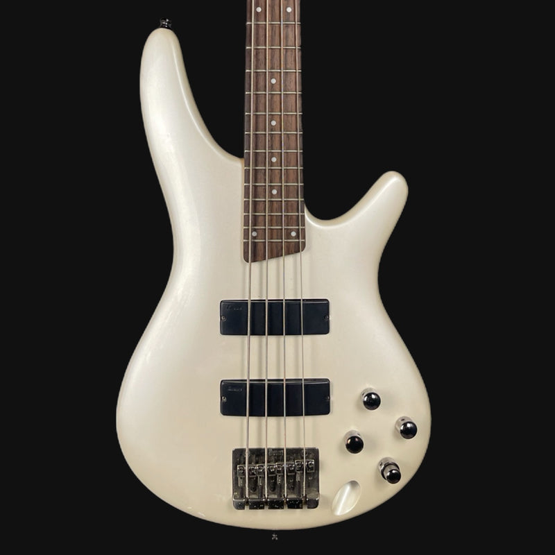 White bass guitar with a black pickguard on a white background