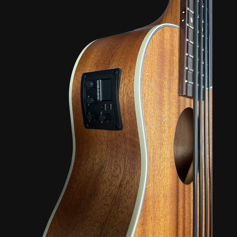 Close-up of a wooden electric bass guitar on a black background