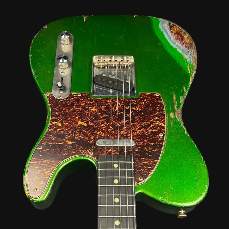 Green electric guitar with a worn finish on a black background