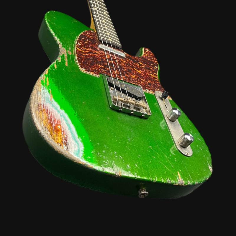 Green electric guitar with a worn finish on a black background