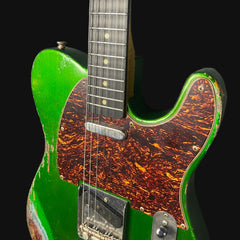 Green electric guitar with tortoiseshell pickguard on a black background
