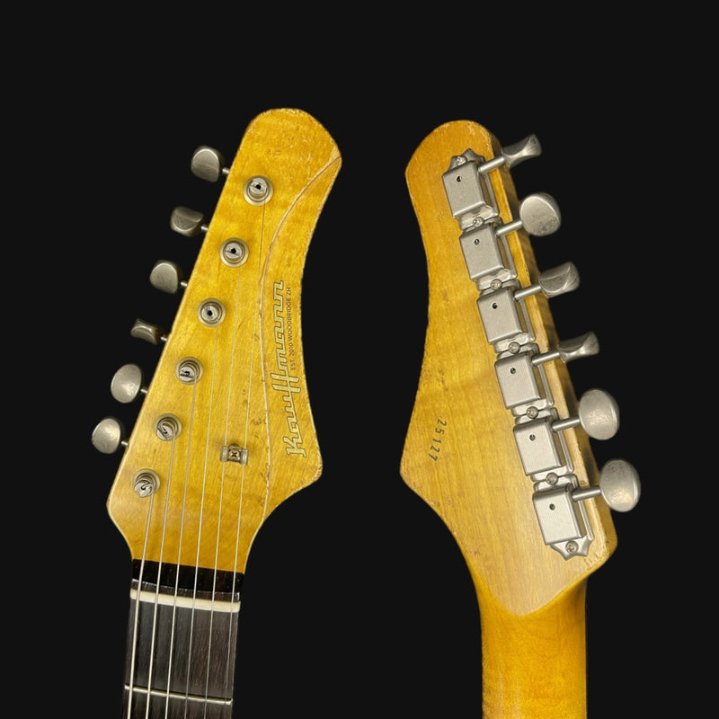 Close-up of two guitar heads with brand names on a black background