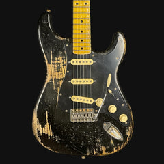 Worn electric guitar with a black and gold finish on a black background