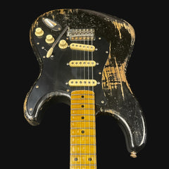 Distressed electric guitar with black and gold finish on a black background
