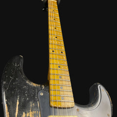 Close-up of a guitar with a worn finish on a black background