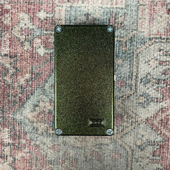 Black rectangular object with textured surface on a patterned fabric background