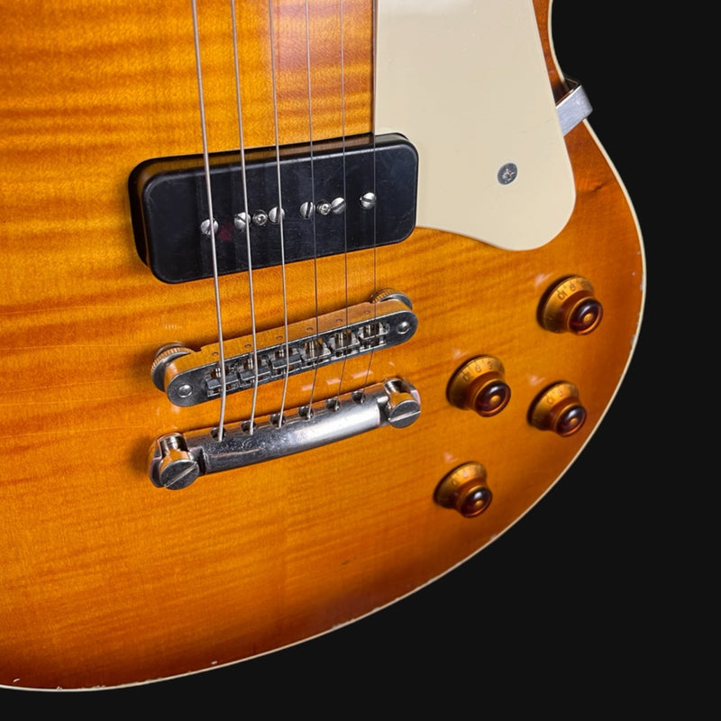 Close-up of a guitar's bridge and tuning pegs on a black background