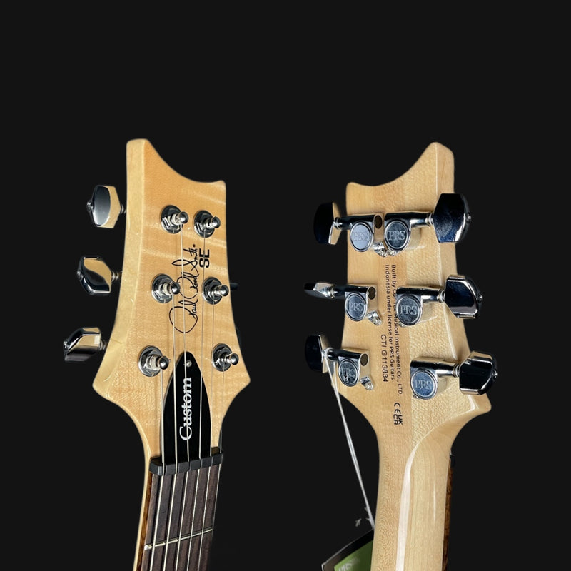 Close-up of two electric guitar heads with visible brand names on a black background