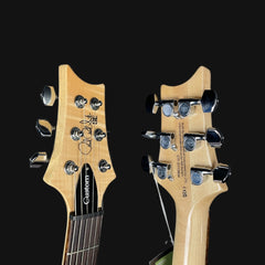 Close-up of two electric guitar heads with visible brand names on a black background