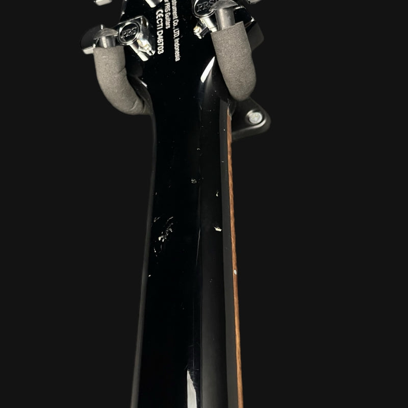 Close-up of a guitar neck with headstock on a black background