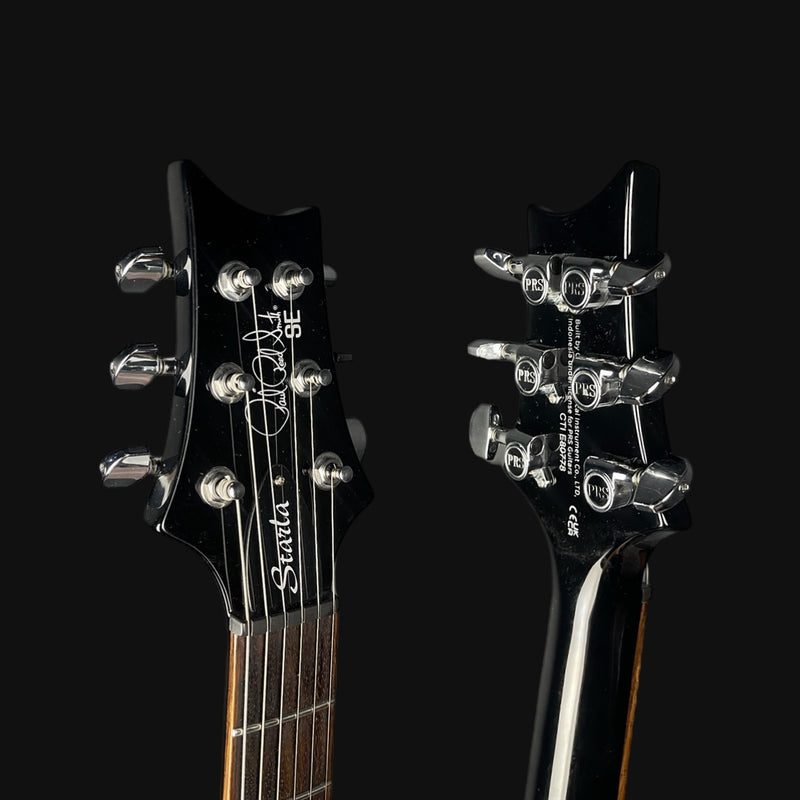 Two black electric guitars with visible brand names on a black background