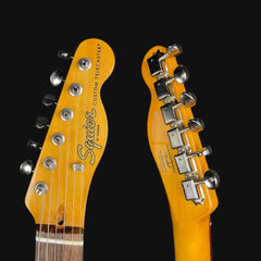 Close-up of two guitar heads with 'Squier' branding on a black background