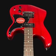 Red electric guitar with a black pickguard on a black background