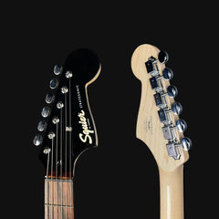 Close-up of two guitar heads with 'Squier' branding on a black background
