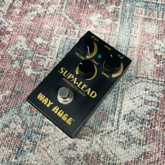 Way Huge Supa-Lead guitar effects pedal on a patterned surface