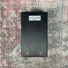 Black rectangular battery pack with CE and FCC labels on a patterned carpet