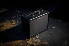 Black guitar amplifier on a textured surface with a dark background