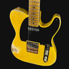 Yellow electric guitar with a black pickguard on a black background